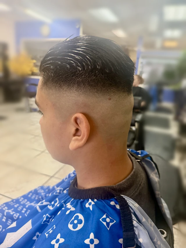 Boy’s combed side-part haircut with a close fade, viewed from the rear side.