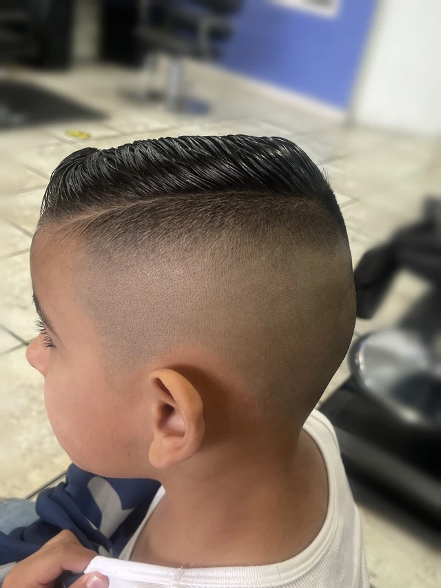 Boy’s combed side-part haircut with closely faded sides, viewed in profile.