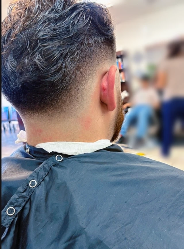Textured wavy haircut with faded sides and nape, viewed from behind.