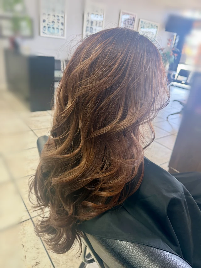 Long brunette waves with warm highlights, viewed from behind at an angle.
